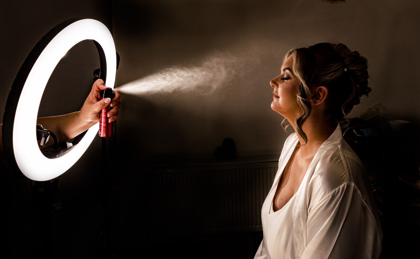 Bride having her hair finished under a ring light before the ceremony