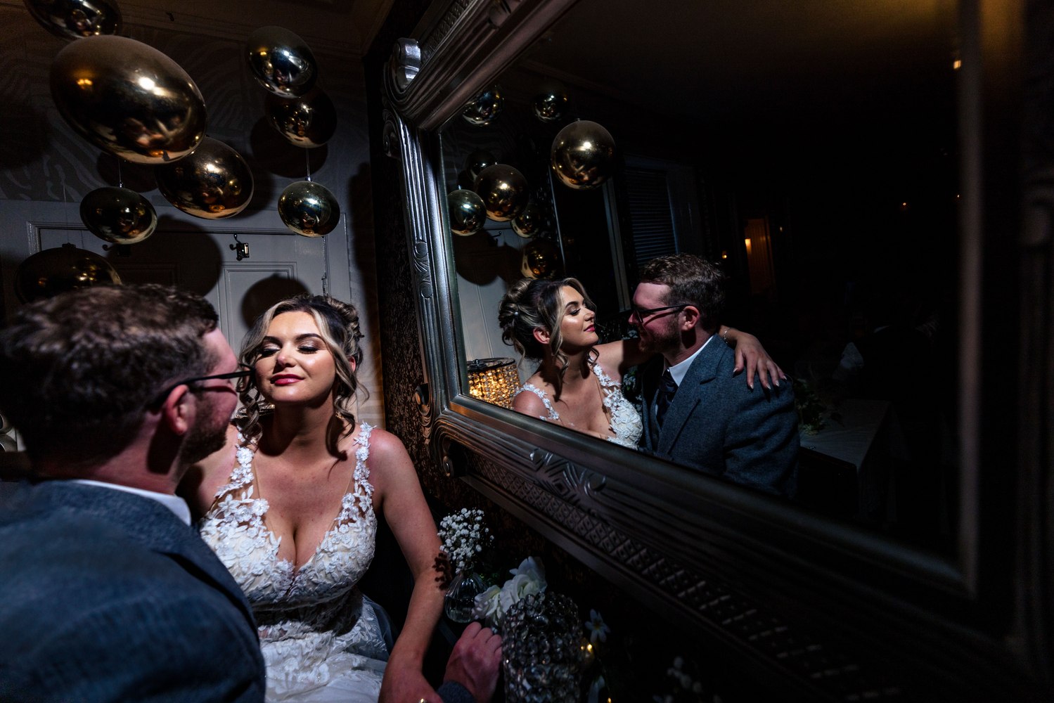 Bride and groom sharing a moment beside an ornate mirror at their reception